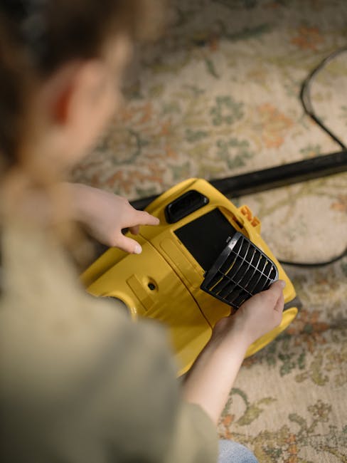A person operating a yellow portable industrial blower on a patterned stone or tile floor, likely during a cleaning or drying process. The blower has a black grille for airflow, and the individual is holding it with both hands, focusing on surface cleaning or moisture removal. The surrounding environment appears to be an indoor space with a textured, multicolored stone or tile floor, and soft lighting highlights the clean surface. This scene exemplifies professional deep cleaning and surface sanitisation, typical of services provided by Cleaners St. John's Wood, aimed at ensuring hygienic and spotless interiors.